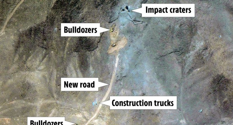 Aerial view of construction activity showing bulldozers, construction trucks, a new road, and impact craters.