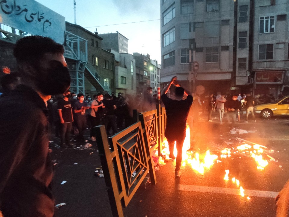 Protestors at night burning debris in a city street.