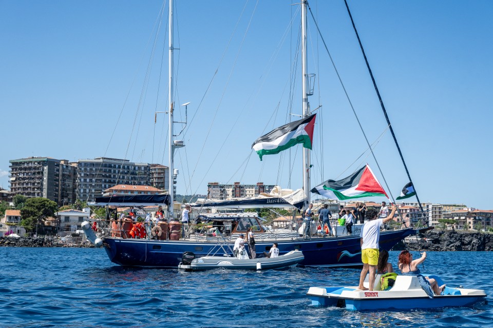 CATANIA, ITALY - JUNE 01: Just before the departure of the Madleen, the Freedom Flotilla vessel, a young man raises the Palestinian flag from a pedal boat as other boats fly the same flag off the port of San Giovanni Li Cuti on June 01, 2025 in Catania, Italy. Swedish activist Greta Thunberg is among those who will attempt to sail to Gaza on a boat organized by the Freedom Flotilla Coalition (FFC), in a bid to break Israel's blockade of the Palestinian territory. Freedom Flotilla had to abort a previous journey in early May after it said its boat came under attack by drones in international waters near Malta. (Photo by Fabrizio Villa/Getty Images)