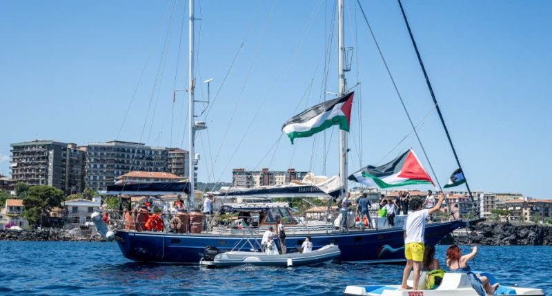 CATANIA, ITALY - JUNE 01: Just before the departure of the Madleen, the Freedom Flotilla vessel, a young man raises the Palestinian flag from a pedal boat as other boats fly the same flag off the port of San Giovanni Li Cuti on June 01, 2025 in Catania, Italy. Swedish activist Greta Thunberg is among those who will attempt to sail to Gaza on a boat organized by the Freedom Flotilla Coalition (FFC), in a bid to break Israel's blockade of the Palestinian territory. Freedom Flotilla had to abort a previous journey in early May after it said its boat came under attack by drones in international waters near Malta. (Photo by Fabrizio Villa/Getty Images)