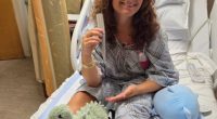 Young woman in hospital gown holding beach umbrella pole that impaled her.
