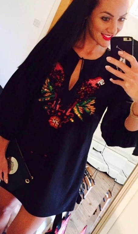 Selfie of a woman wearing an embroidered black dress.