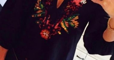 Selfie of a woman wearing an embroidered black dress.