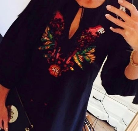 Selfie of a woman wearing an embroidered black dress.