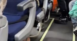 Airplane aisle with passengers seated.