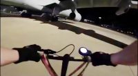 First-person view of a person riding a bike at night near airplanes.