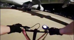 First-person view of a person riding a bike at night near airplanes.