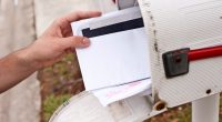 A hand retrieving mail from a mailbox.