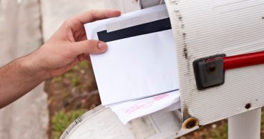 A hand retrieving mail from a mailbox.