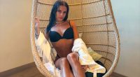 Woman in black bikini top and white robe sitting in a wicker chair.