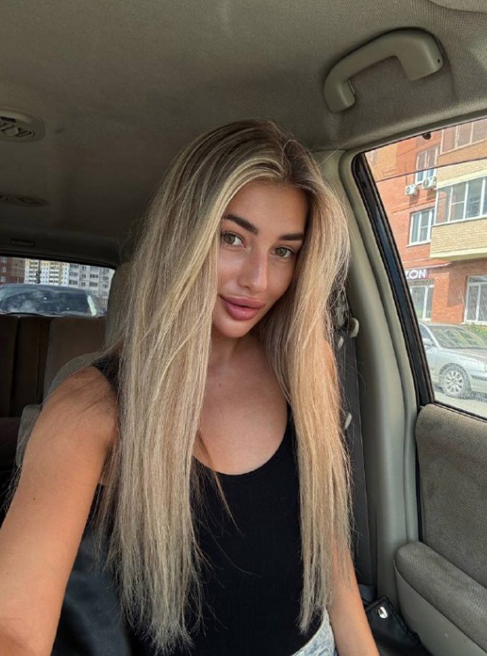 Photo of a young woman with long blonde hair sitting in a car.