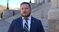 Man in suit speaking outside a government building.