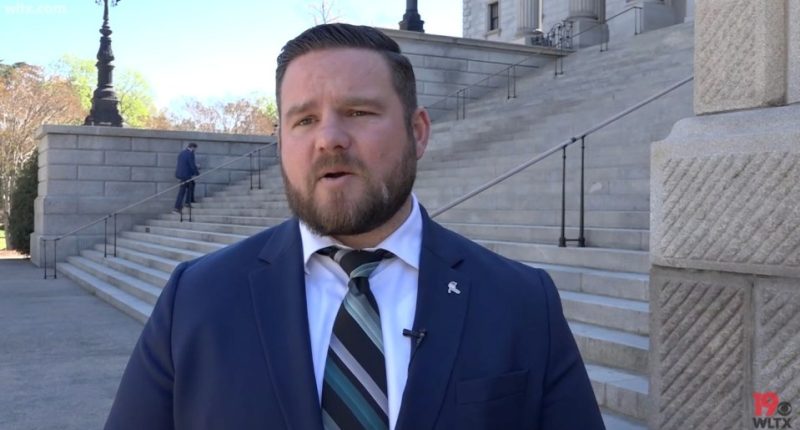 Man in suit speaking outside a government building.