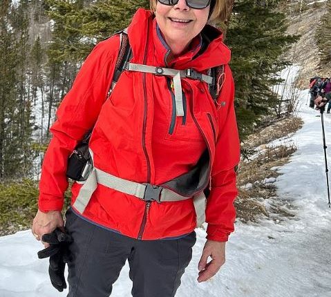Woman in red jacket hiking in the snow.