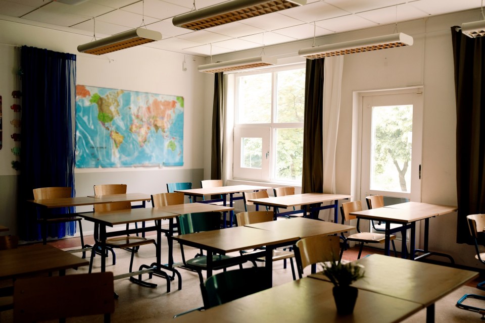 Empty classroom with desks and chairs arranged in rows.