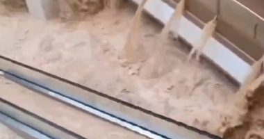 Floodwaters rushing through a shopping mall, submerging escalators.