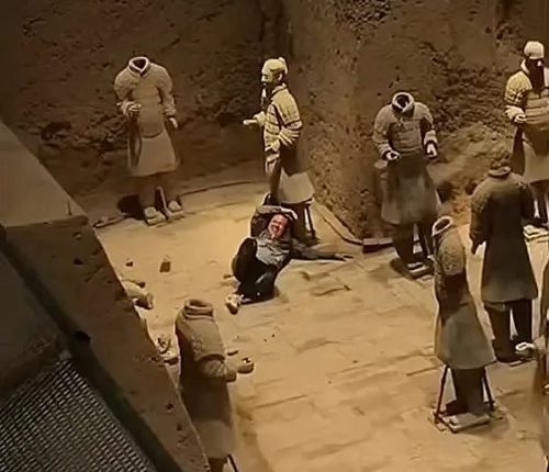 A person sitting among damaged terracotta army statues.