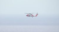 Coast Guard helicopter in flight over water.