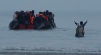 Migrants in a small boat approaching the shore.