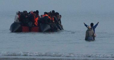 Migrants in a small boat approaching the shore.