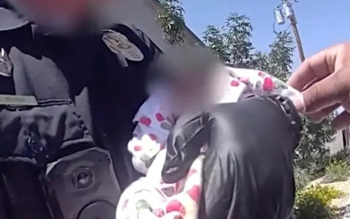 Police officer rescuing an emaciated newborn baby.