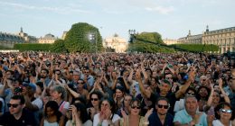 People clap as they gather to listen to music prior to the reinstallation and lift-off of the 2024 Olympic cauldron during a free concert to mark France's annual street music festival, 'Fete de la Musique', at the Jardin des Tuileries, in Paris on June 21, 2025. (Photo by GEOFFROY VAN DER HASSELT / AFP) (Photo by GEOFFROY VAN DER HASSELT/AFP via Getty Images)