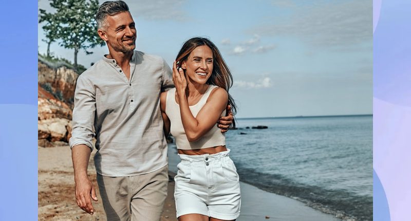 Happy attractive couple walking on beautiful sunny beach. Copy space