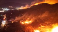 Firefighters battling a large wildfire at night.