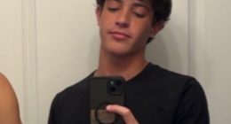 A young man taking a selfie in a bathroom mirror.
