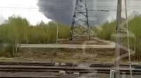 Large plume of smoke rising near a railway and power lines.
