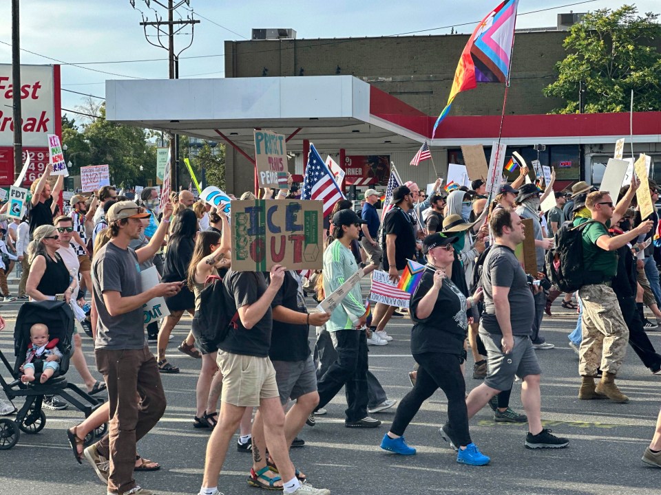 Protestors march carrying signs.