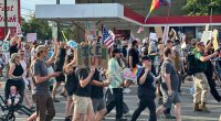 Protestors march carrying signs.