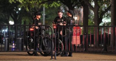 Secret Service officers on bicycles stand guard at a barricade.