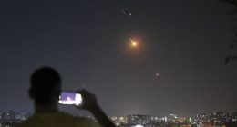 A man takes a cellphone photo as missiles fired from Iran toward Israel fly over Syrian territory in Damascus, Syria, early Wednesday, June 18, 2025. (AP Photo/Ghaith Alsayed)