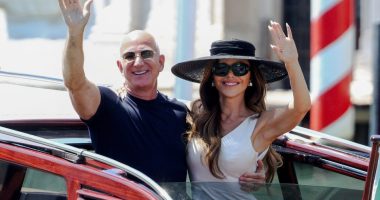 Jeff Bezos and Lauren Sanchez waving from a boat in Venice.
