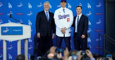 Los Angeles Dodgers' Shohei Ohtani, center, poses for a photo with owner and chairman Mark Walter, left, and president of baseball operations Andrew Friedman applaud during a news conference at Dodger Stadium Thursday, Dec. 14, 2023, in Los Angeles. (AP Photo/Ashley Landis)
