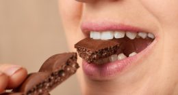 Close-up of a woman biting a piece of chocolate.