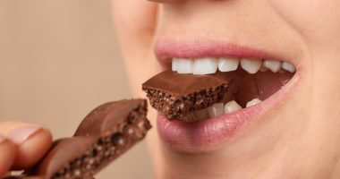 Close-up of a woman biting a piece of chocolate.