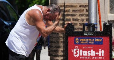 Man cooling off under a sprinkler during hot weather.