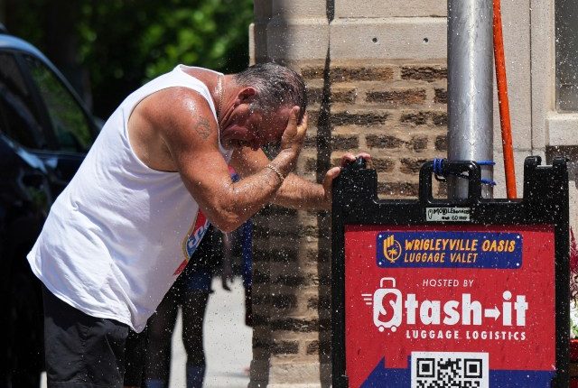 Man cooling off under a sprinkler during hot weather.