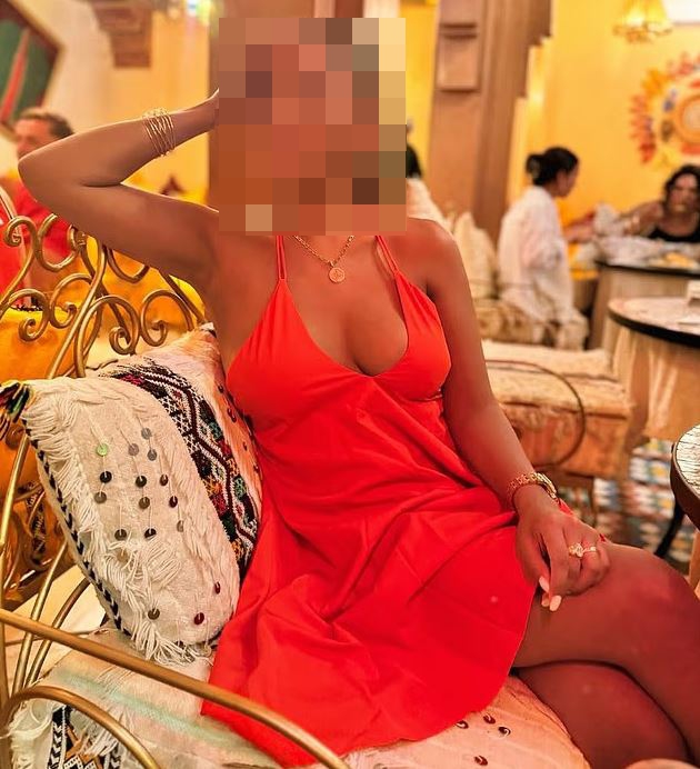 Woman in orange dress with face blurred.