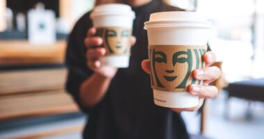 Jun 13th 2022 : Closeup of a woman holding and serving two cup of hot coffee at Starbucks coffee shop, Chiang mai Thailand