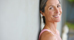 Happiness is an inside job. Portrait of an attractive mature woman in gymwear leaning against a gray wall.
