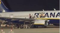 Passengers evacuating a Ryanair plane on the tarmac.