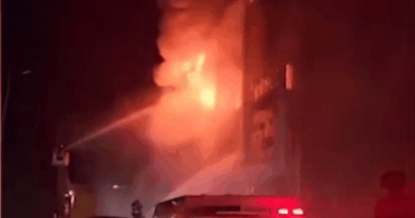 Firefighters battling a large building fire at night.