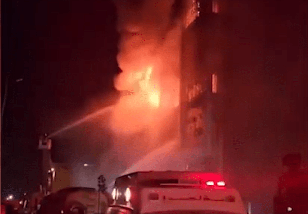 Firefighters battling a large building fire at night.