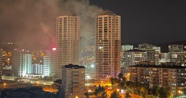 Nighttime view of a city with smoke rising from a building fire.