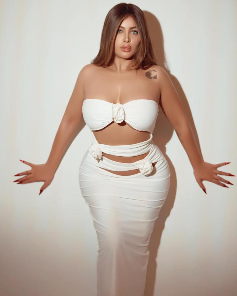 Woman in white dress against a white wall.