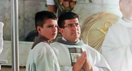 A priest and altar boy in white robes.