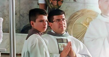 A priest and altar boy in white robes.